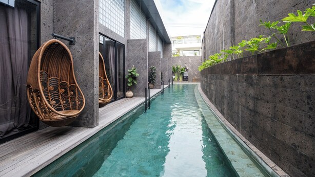 A narrow indoor pool with wicker chairs and potted plants. - The Lima Ocean Suites Pererenan (Canggu)