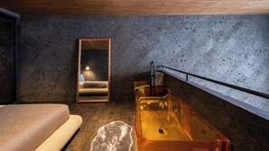 A modern bathroom with a bathtub, a mirror, and a textured wall. - The Lima Ocean Suites Pererenan (Canggu)