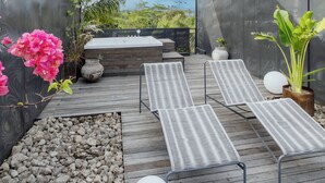 A rooftop garden with a wooden deck, lounge chairs, a hot tub, and potted plants. - The Lima Ocean Suites Pererenan (Canggu)