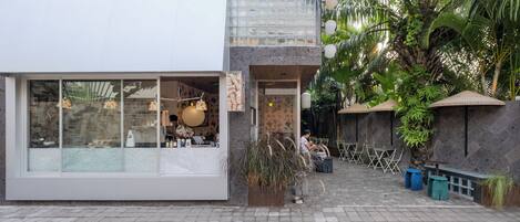A modern building with large glass windows, a stone facade, and outdoor seating.