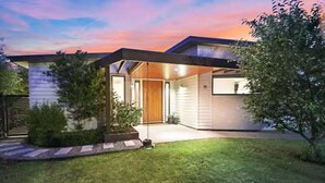 Een modern huis met een overdekte veranda, een houten deur en een verzorgd gazon.