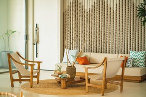 Ein modernes Wohnzimmer mit einer Couch, zwei Holzstühlen, einem Couchtisch und einer Wanddekoration.