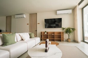 Uma sala de estar moderna com sofá, mesa de centro e televisão de tela plana na parede.