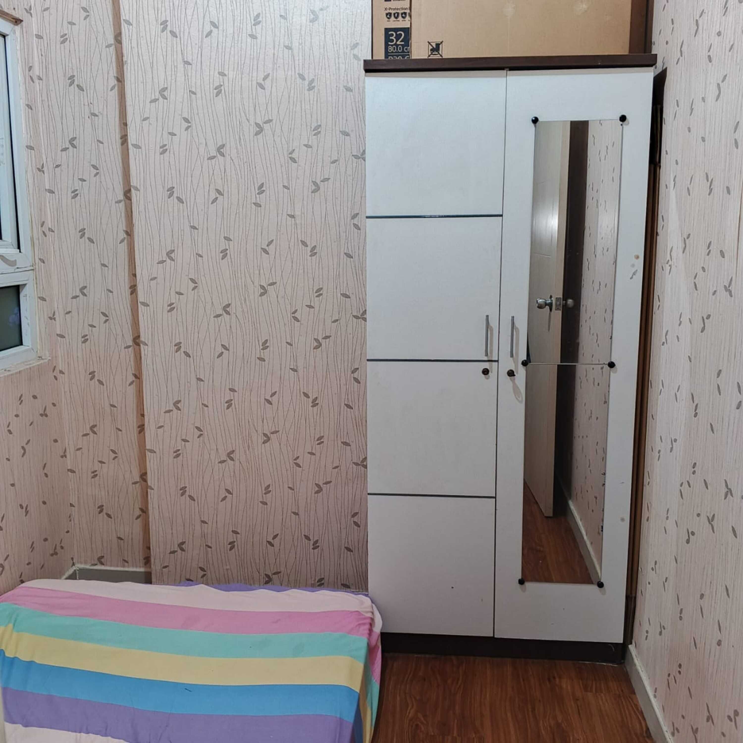 Une chambre avec un lit, une armoire et une fenêtre.