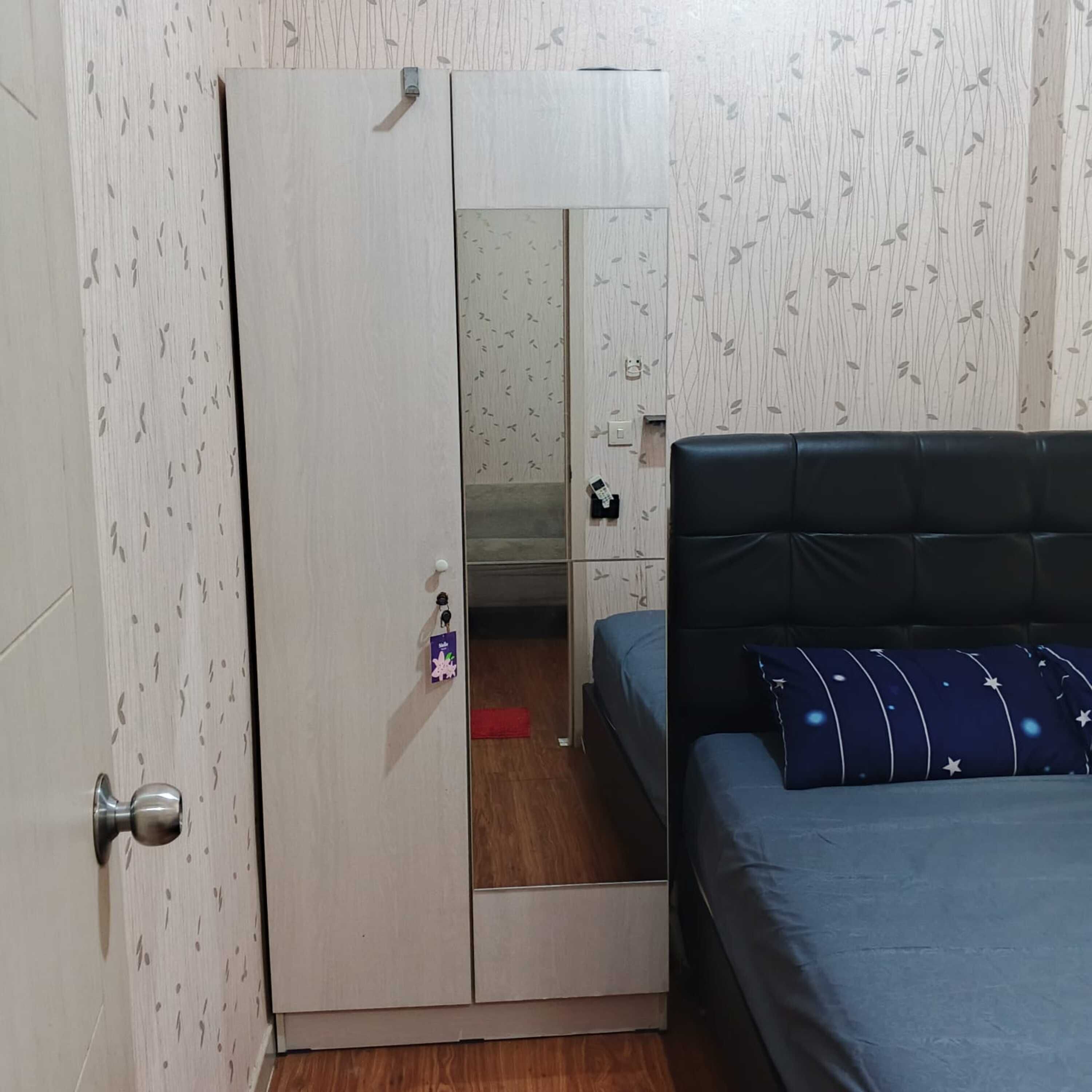 A bedroom with a wardrobe, a bed, and a mirror.