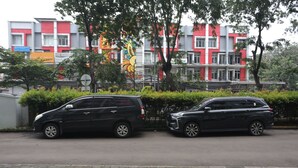 Two parked cars on a paved road with a colorful building in the background.