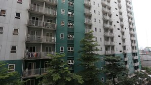 A multi-story residential building with balconies, windows, and a green facade.