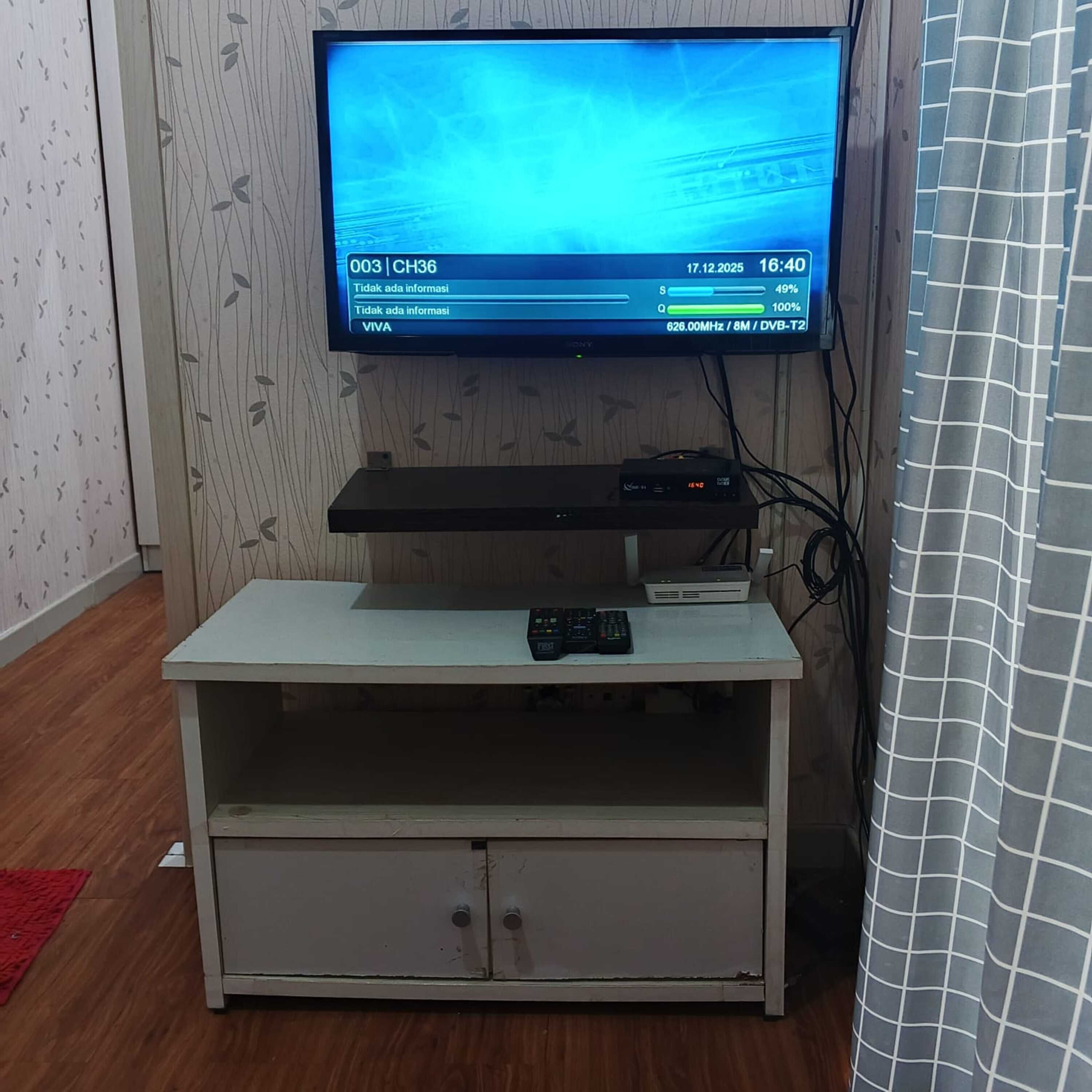 A television on a white entertainment center with a remote control.