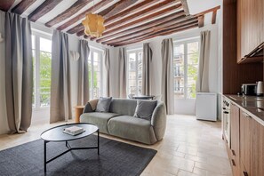 Una sala de estar moderna con un sofá, una mesa de centro y una zona de cocina con refrigerador y estufa.
