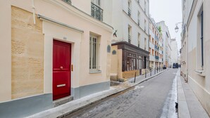 Une rue étroite, bordée de bâtiments des deux côtés, avec une porte rouge et une piste cyclable.