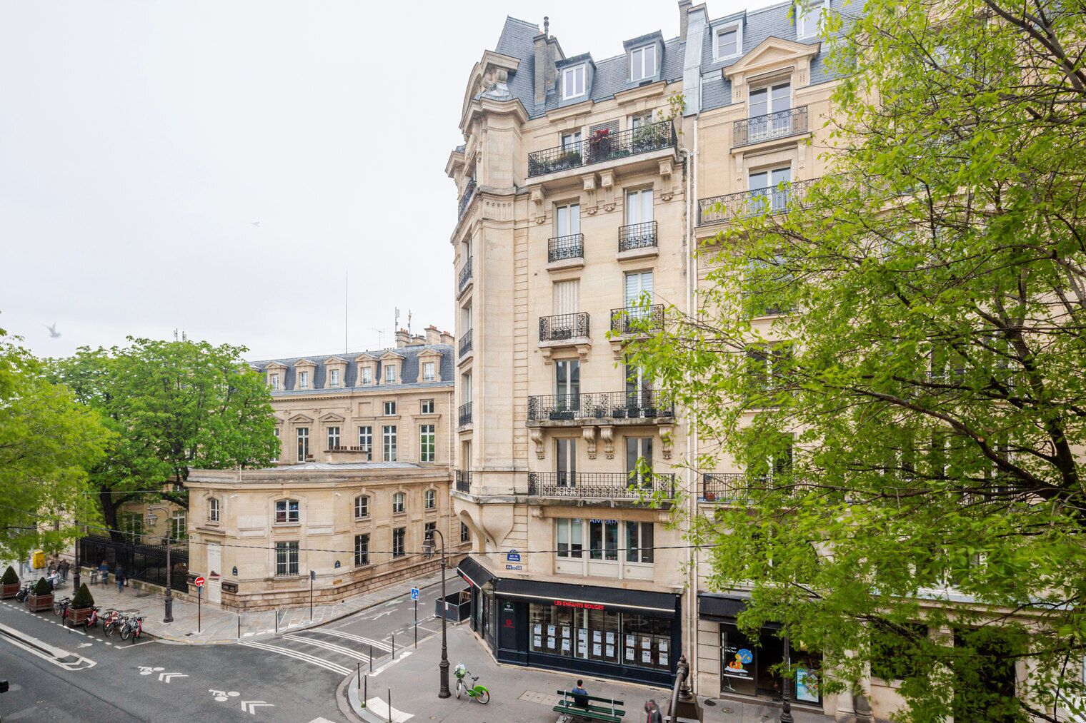 A multi-story building with a classic architectural style, featuring balconies and a ground-floor shop.