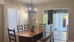 Un comedor con una mesa de madera, sillas, una araña y vistas a un patio.
