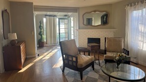 Una sala de estar con chimenea, ventilador de techo y vistas al exterior.