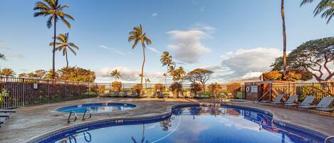 A swimming pool with lounge chairs and palm trees.