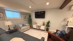 En stue med sofa, fjernsyn, lampe og en plante.