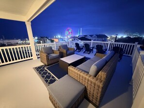 A covered outdoor seating area with wicker furniture and a view of a Ferris wheel.