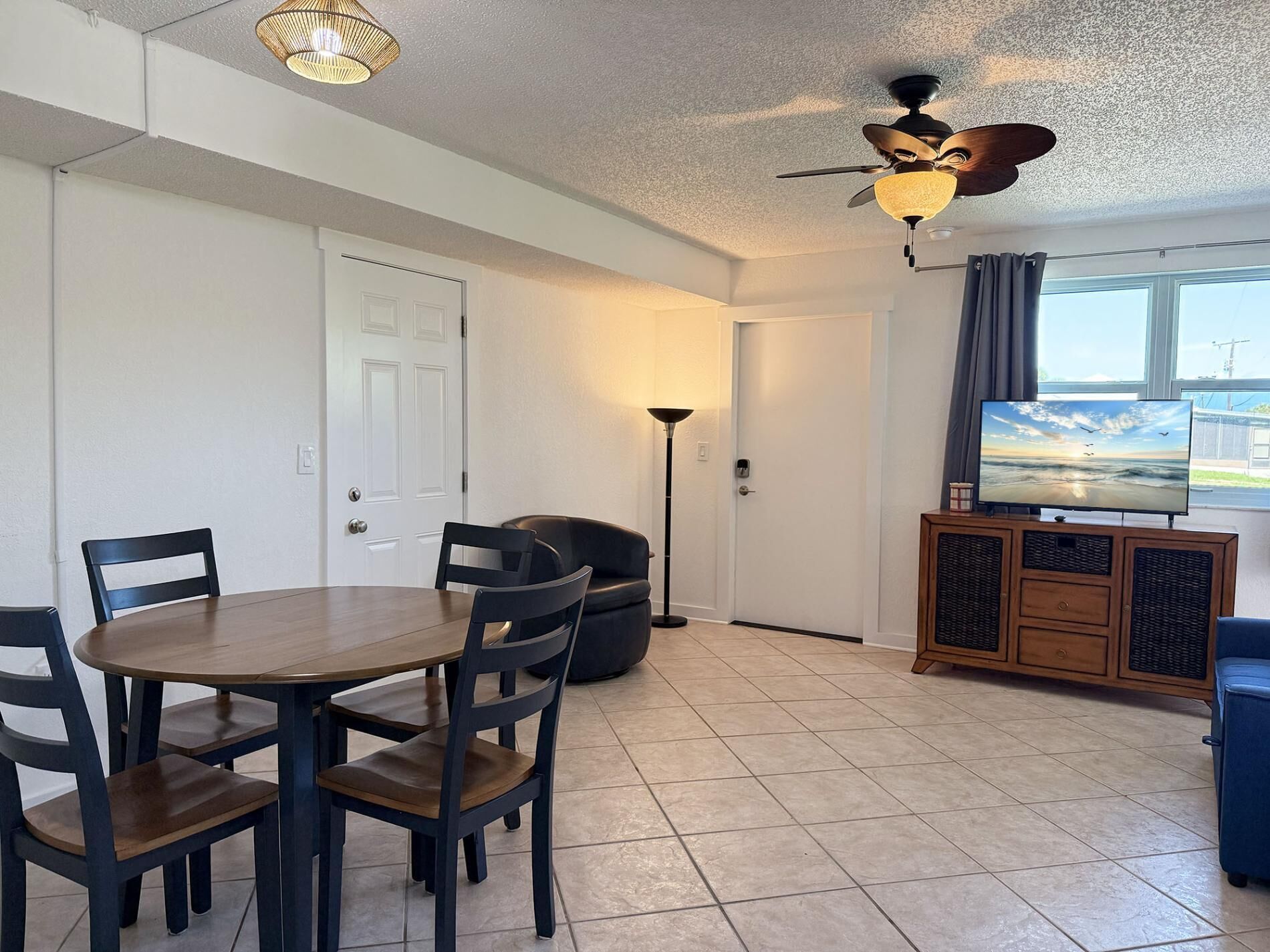 A room with a dining table, chairs, a ceiling fan, a TV, and a window with a view.