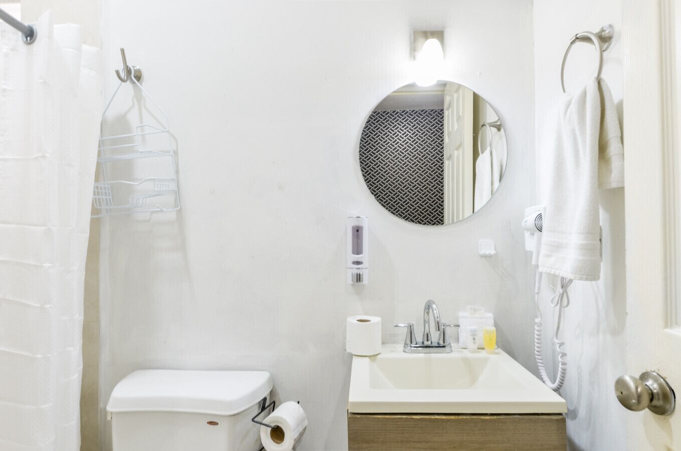 Un baño con inodoro, lavabo, espejo, toallero y cortina de ducha.