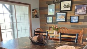 A kitchen with wooden cabinets, a marble countertop, and a dining area with chairs and a table.