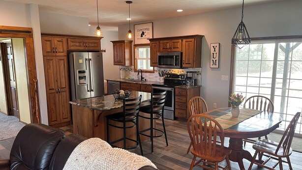 A modern kitchen with wooden cabinets, stainless steel appliances, and a dining area with a table and chairs.