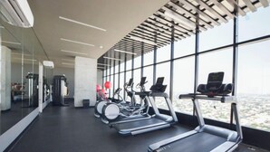 Een fitnessruimte met loopbanden, hometrainers en een spiegelwand.