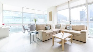 Un salon moderne comprenant un canapé d’angle, une table basse et un coin repas avec des chaises et une table.