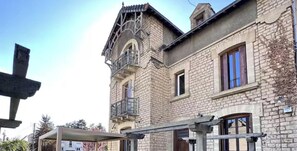 Ein Gebäude aus Stein mit einem Balkon, einem überdachten Außenbereich und einem Fenster mit Holzklappe.