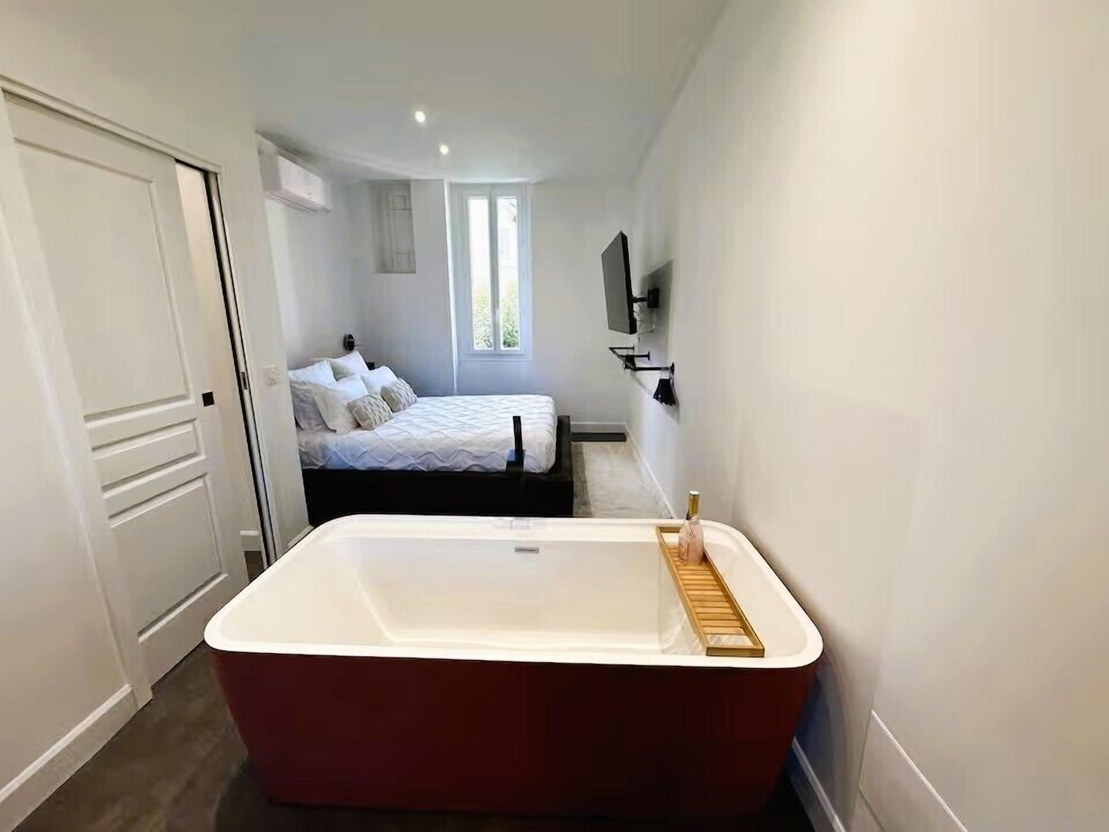 Un baño moderno con una bañera independiente, una zona de ducha y una cama con ventana.