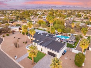 A modern house with a swimming pool, surrounded by palm trees and a desert landscape. - Tropical Villa by Glam Homes (Scottsdale)