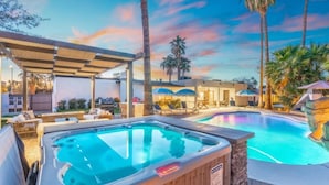 A hot tub and a swimming pool with lounge chairs and umbrellas. - Tropical Villa by Glam Homes (Scottsdale)