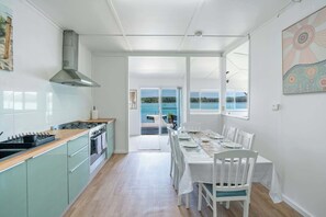 Eine moderne Küche mit Meerblick, ein Essbereich mit weißer Möbel und ein großes Fenster.