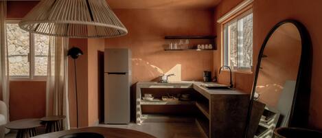 A compact kitchen with a central island, a dining area with a round table, and a large mirror.