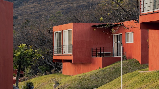 Ein modernes Gebäude mit roter Fassade, großen Fenstern und einem Balkon.