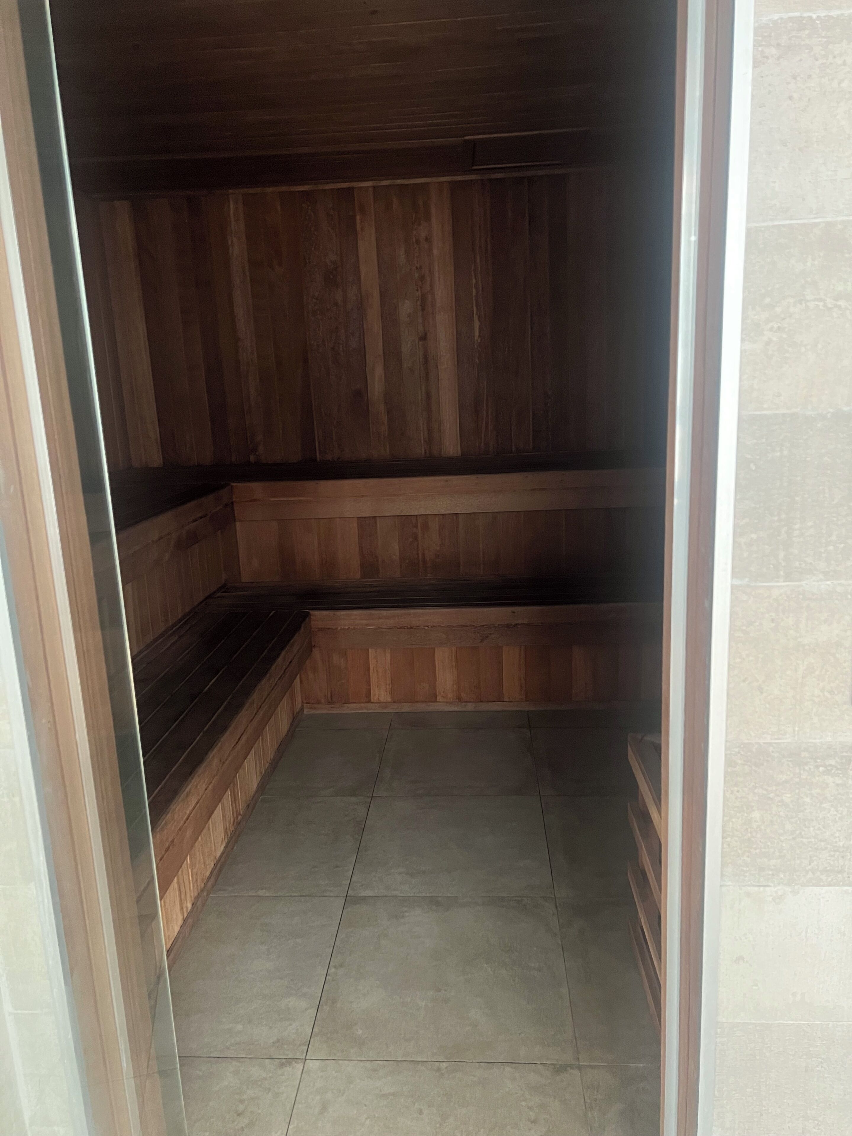 Een kamer met houten lambrisering, een betegelde vloer en een bank langs een muur.