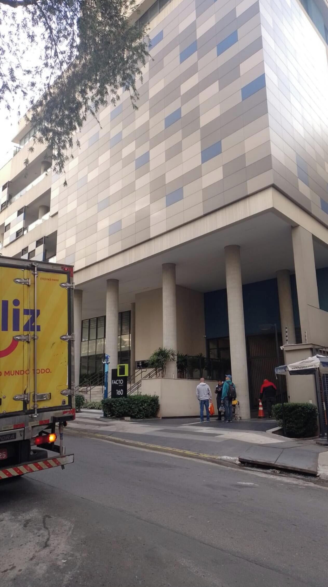 A modern building with a checkered facade, a loading dock, and a few people near the entrance.