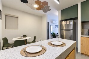 Cozinha moderna com ilha central, área de jantar com cadeiras e geladeira.