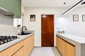 Une cuisine moderne dotée de plans de travail en granit, d’armoires en bois, d’une cuisinière à gaz et d’une porte en bois.