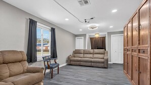 Amplia sala de estar con sofá, sillón y aparador de madera.