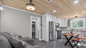 Una cocina moderna con armarios blancos, electrodomésticos de acero inoxidable y una zona de comedor con mesa y sillas de madera.