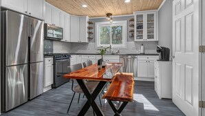 Una cocina moderna con armarios blancos, electrodomésticos de acero inoxidable, techo de madera y un ventanal grande.