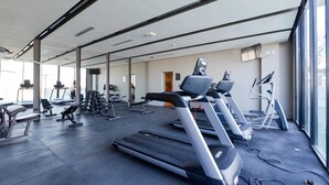 Une salle de sport équipée de tapis de course, d’appareils de musculation et de divers équipements d’exercice.