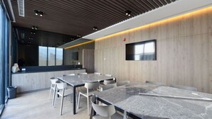 Une salle de conférence moderne, dotée d’une longue table, de chaises blanches, d’un téléviseur à écran plat et d’un mur décoratif en bois.