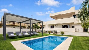 A swimming pool with lounge chairs, a covered seating area, and a modern building with balconies. - VillaMar Salento Room 3 With Pool, Cursi, Italy (Cursi)