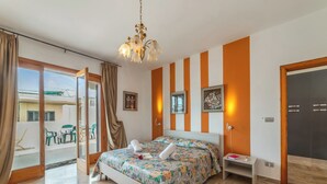 Quarto de hotel com uma cama, mesa de cabeceira, um candelabro e vista por uma porta deslizante.