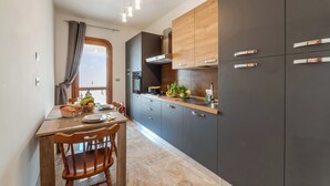 Uma cozinha moderna com armários escuros, uma mesa de jantar de madeira e uma janela com cortinas.