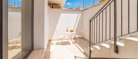 A modern interior with a staircase, a small table with a bottle, and a chair.