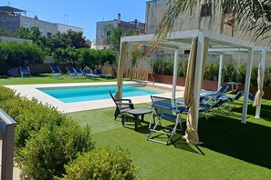 Ein Poolbereich mit Liegestühlen und einer Pergola.