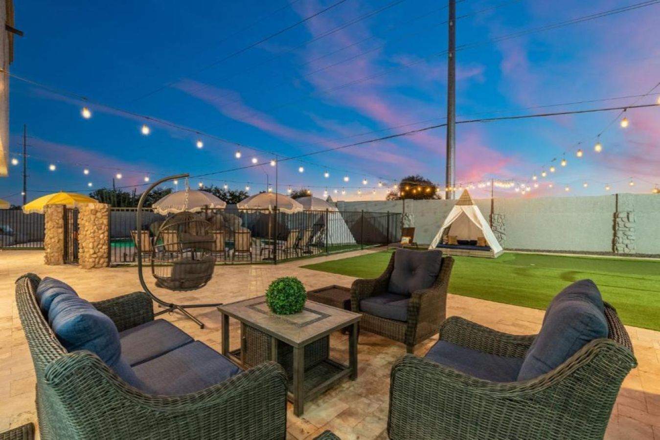 An outdoor patio area with wicker furniture, a small table, and a tent.