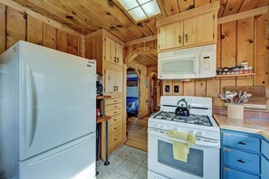 Eine kompakte Küche mit Holzausstattung, einem weißen Kühlschrank, einer Mikrowelle, einem Herd und einem blauen Schrank.