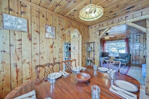 Ein Esszimmer mit Holzwänden, einem runden Tisch für vier Personen, Stühlen und einer Kronleuchter.